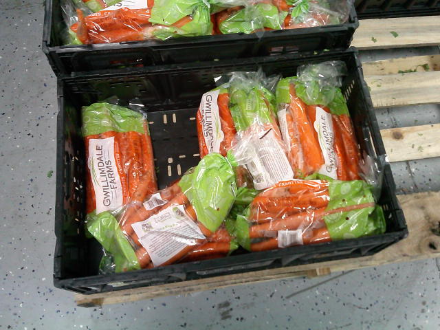 Crates holding bags of whole carrots.